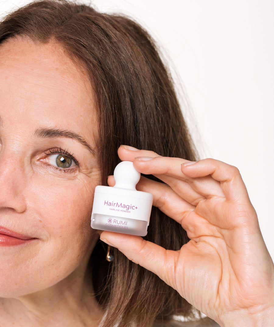Woman over 50 holding the HairMagic+ Hairline Powder compact beside her hairline